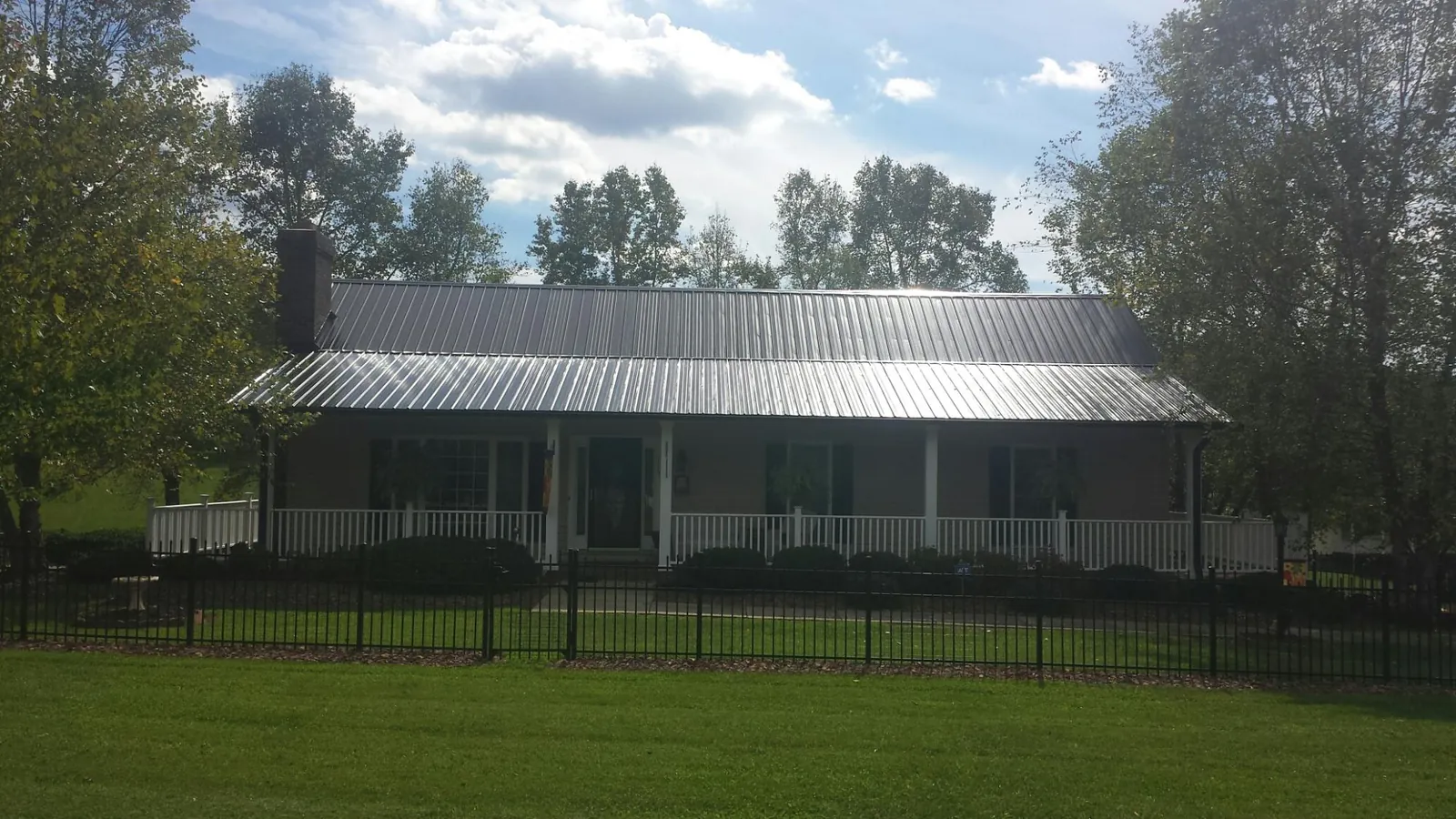 Gray metal roof on a brick ranch with a full width front porch — Gutter Guard Installation work by our crew in Union City